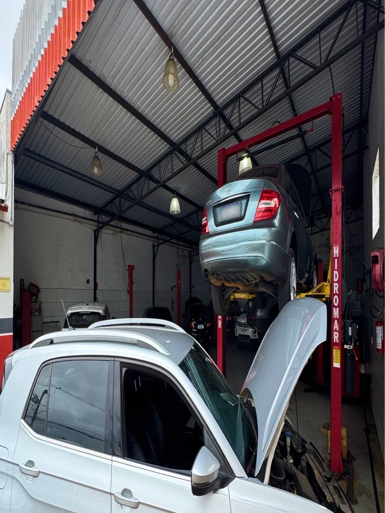 Interior da Mecânica Rios, com veículos em manutenção nos elevadores